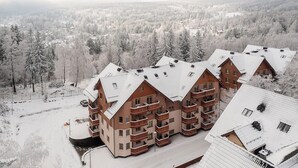 Een hotel met meerdere verdiepingen, een symmetrische gevel, diverse balkons en een besneeuwd landschap op de achtergrond.