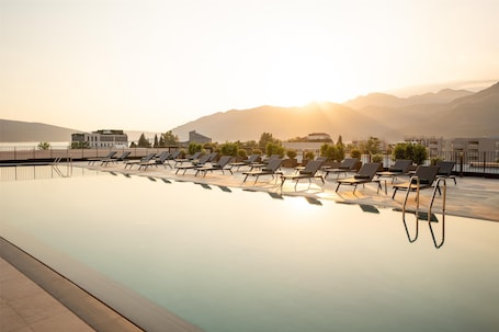 A swimming pool with lounge chairs and a view of mountains and a building in the background.