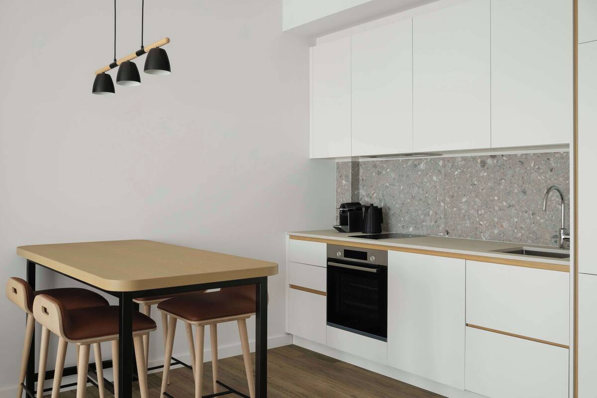 A modern kitchen with white cabinets, a wooden countertop, a built-in oven, and a coffee maker.
