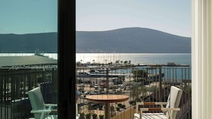 A balcony with a view of a coastal area, including a beach, a pier, and a mountain in the distance. - SIRO Porto Montenegro (Tivat)