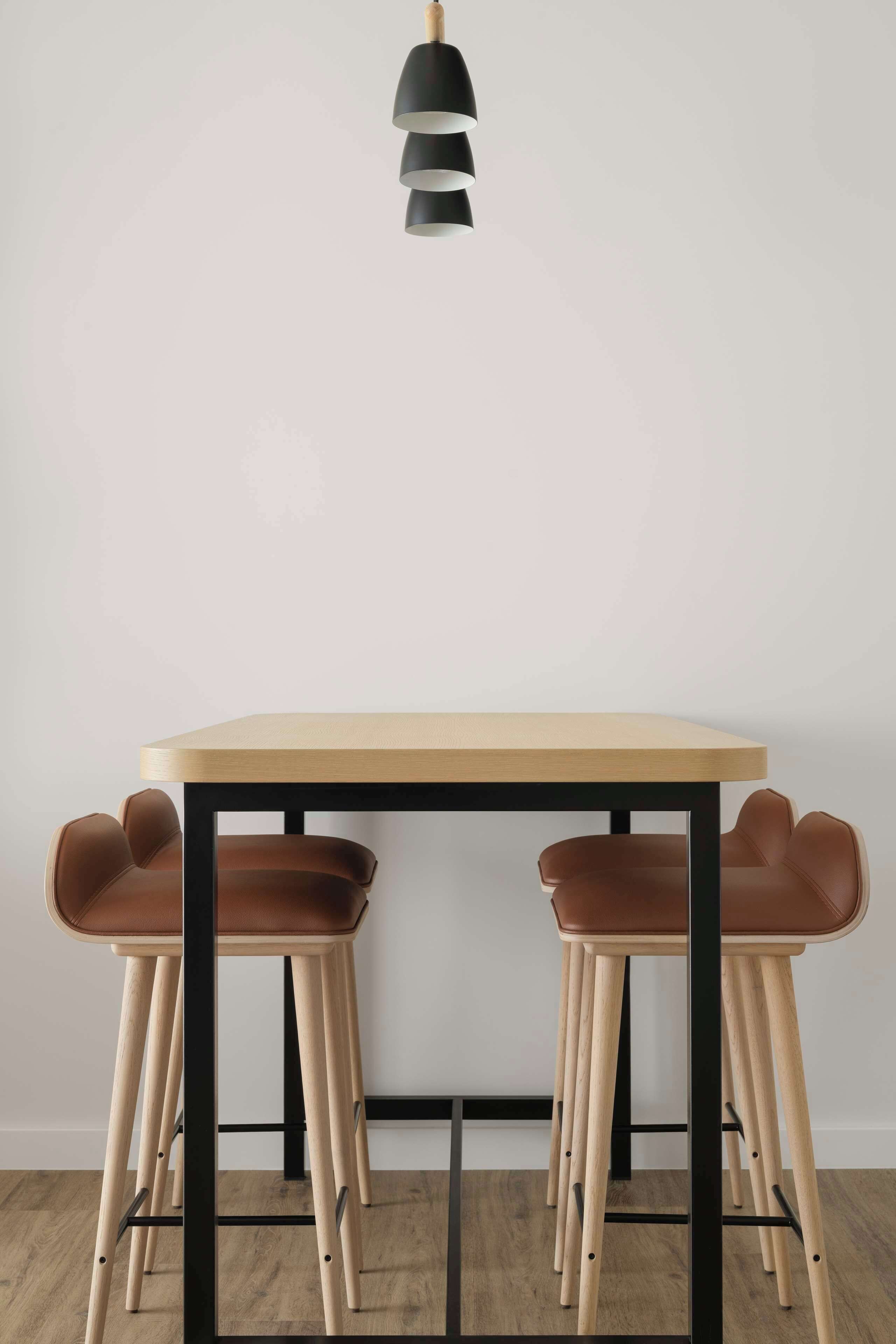 A minimalist dining area with a wooden table and two brown leather chairs.