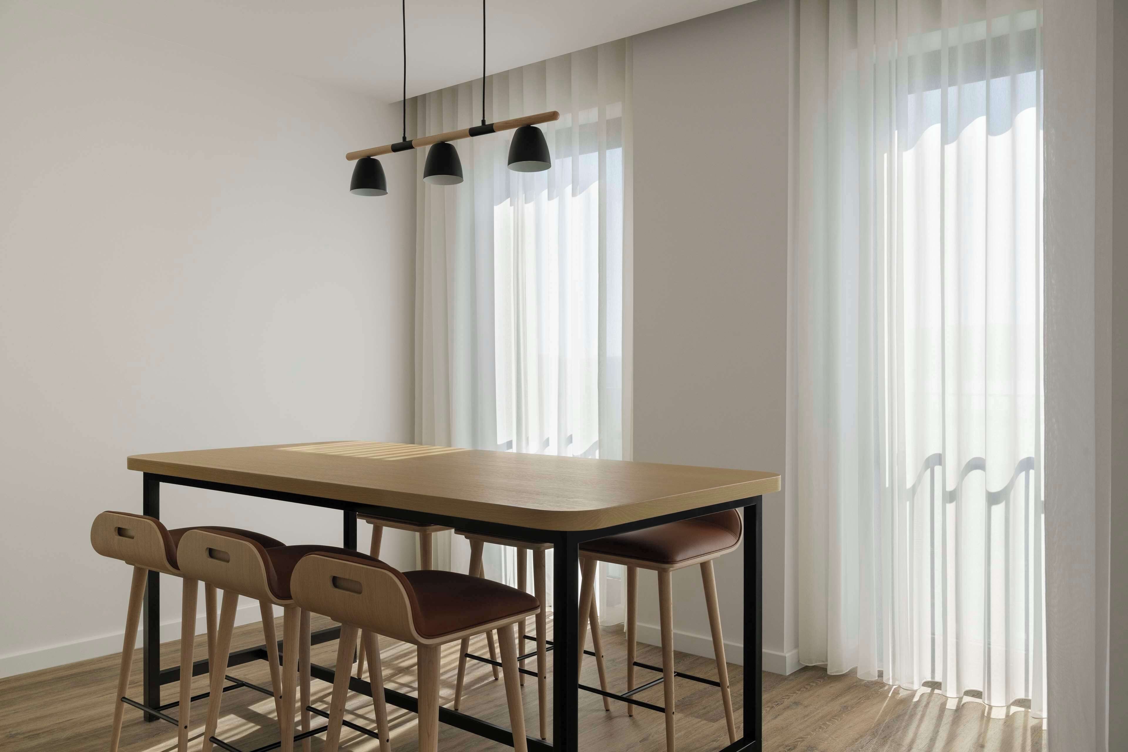 A dining area with a wooden table, four chairs, and a pendant light.