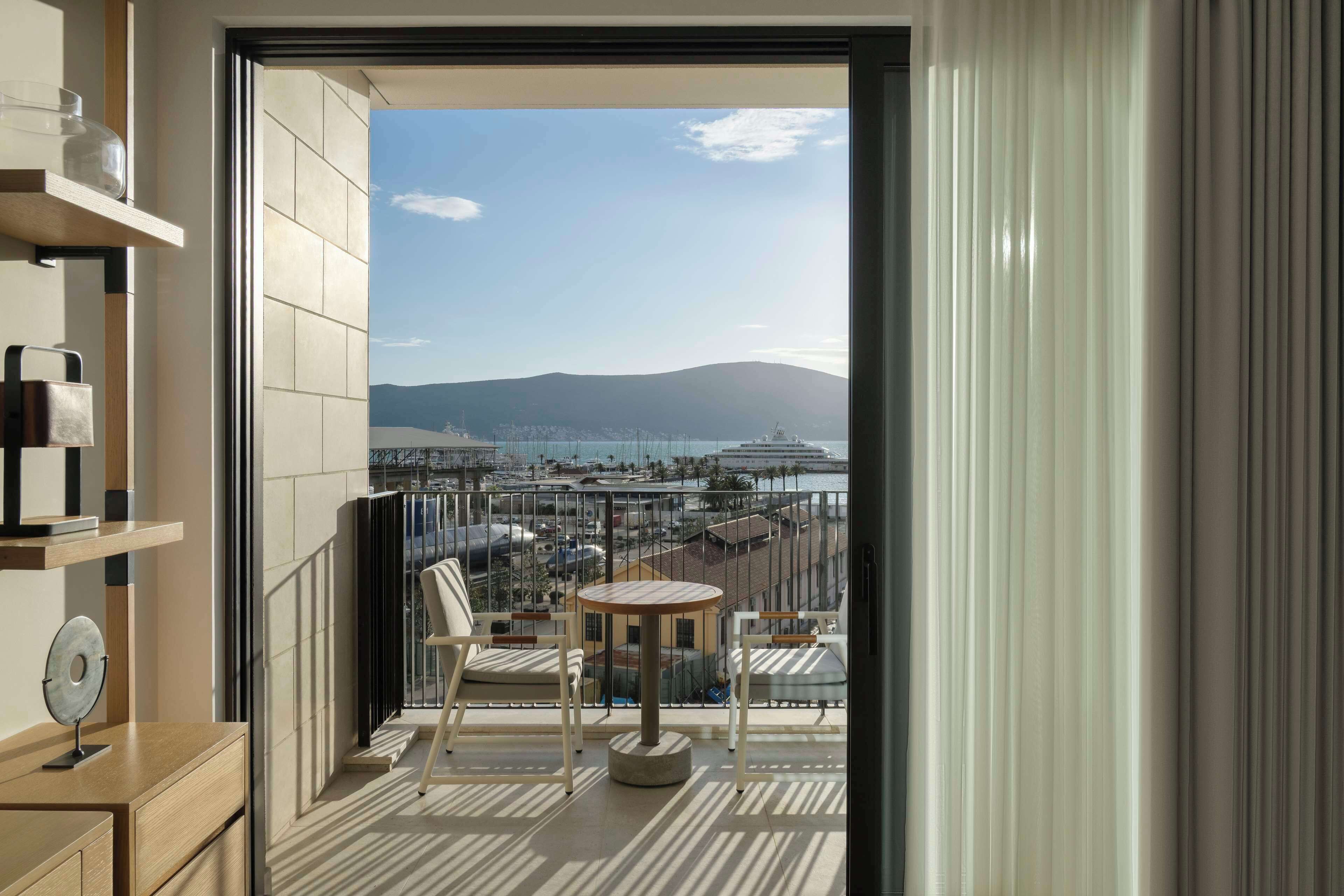 A balcony with a view of a marina and mountains.