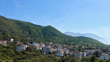 Une ville construite sur une colline, avec des bâtiments nichés au milieu de collines verdoyantes et de montagnes qui se dressent à l’arrière-plan.