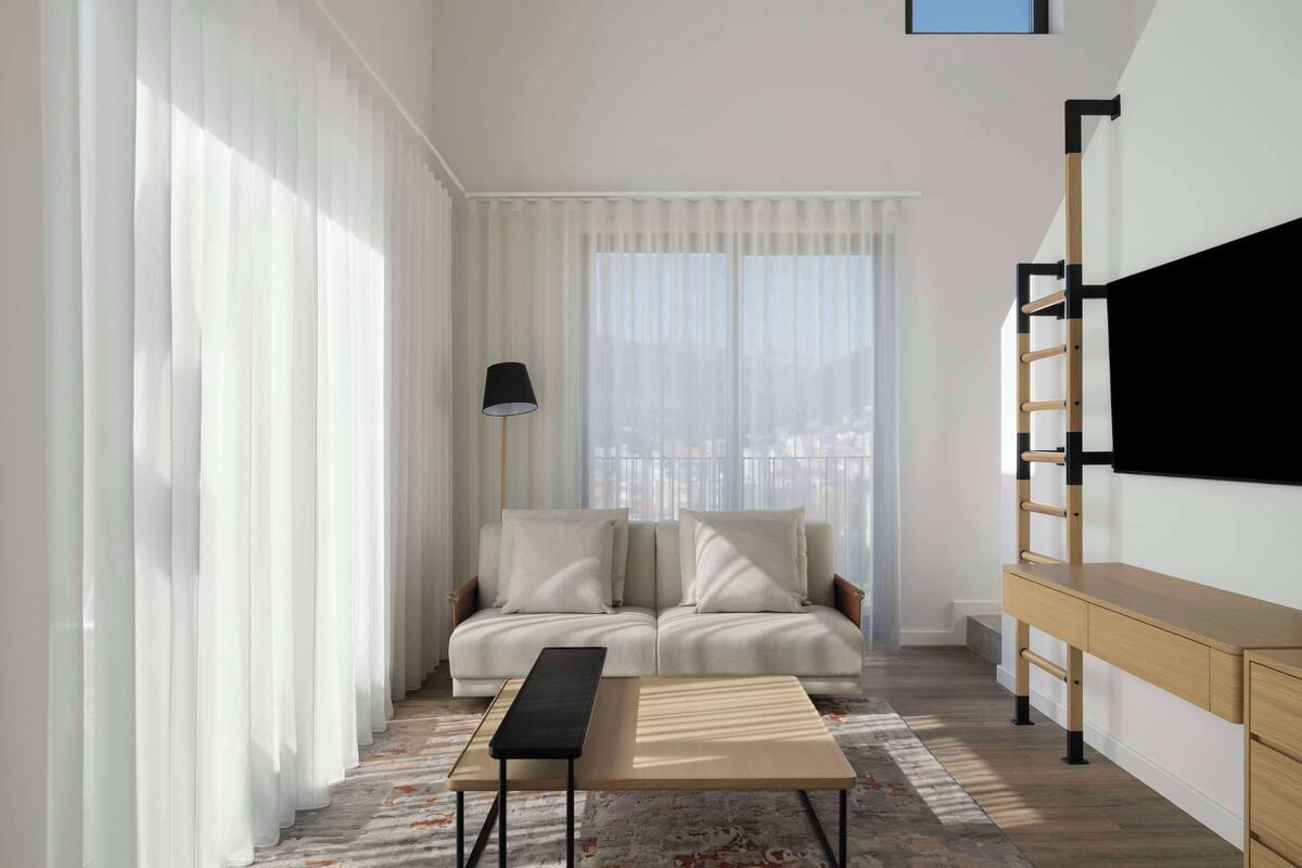 A modern living room with a sofa, a coffee table, and a TV mounted on the wall.