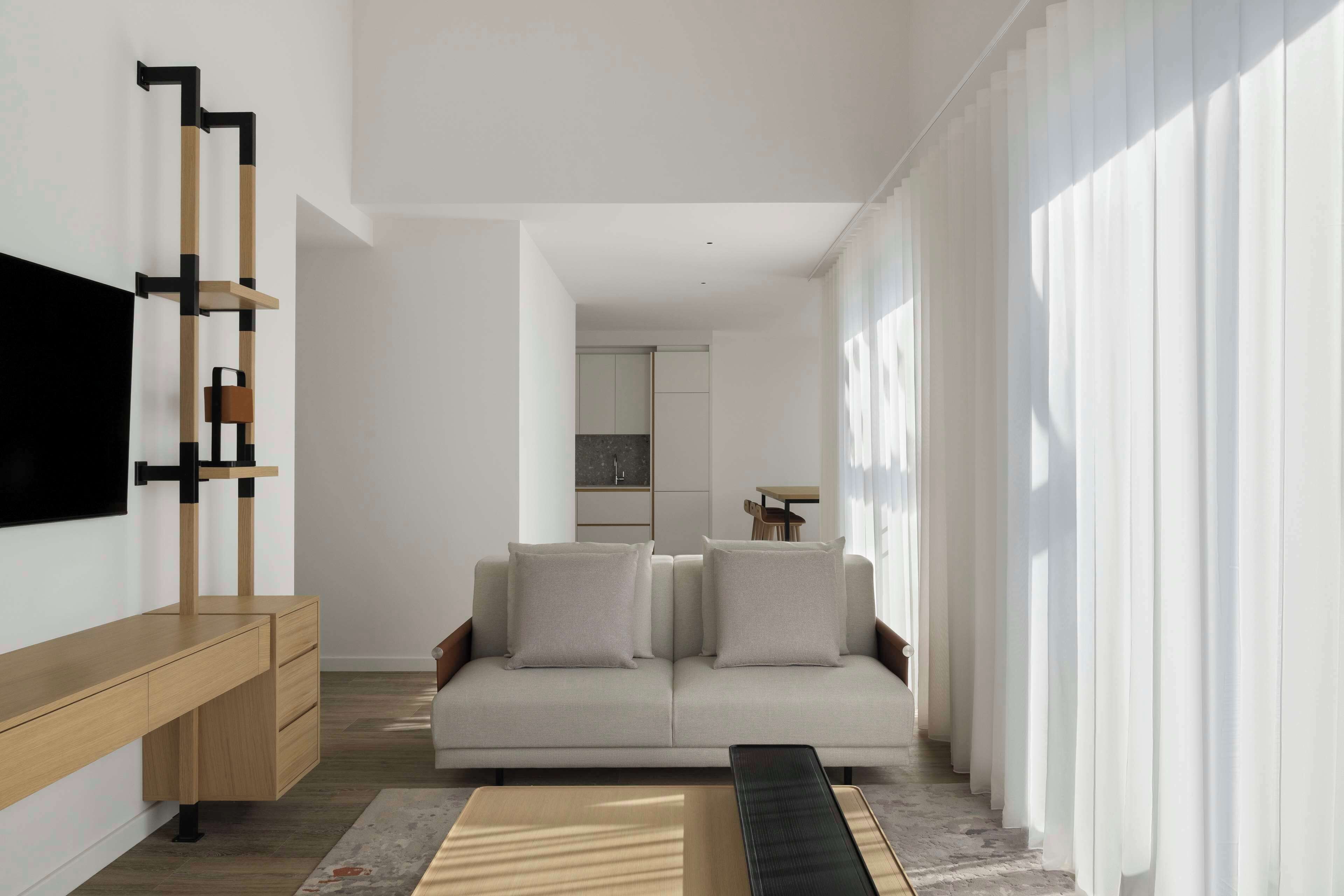 A modern living room with a sofa, TV, and wooden console.