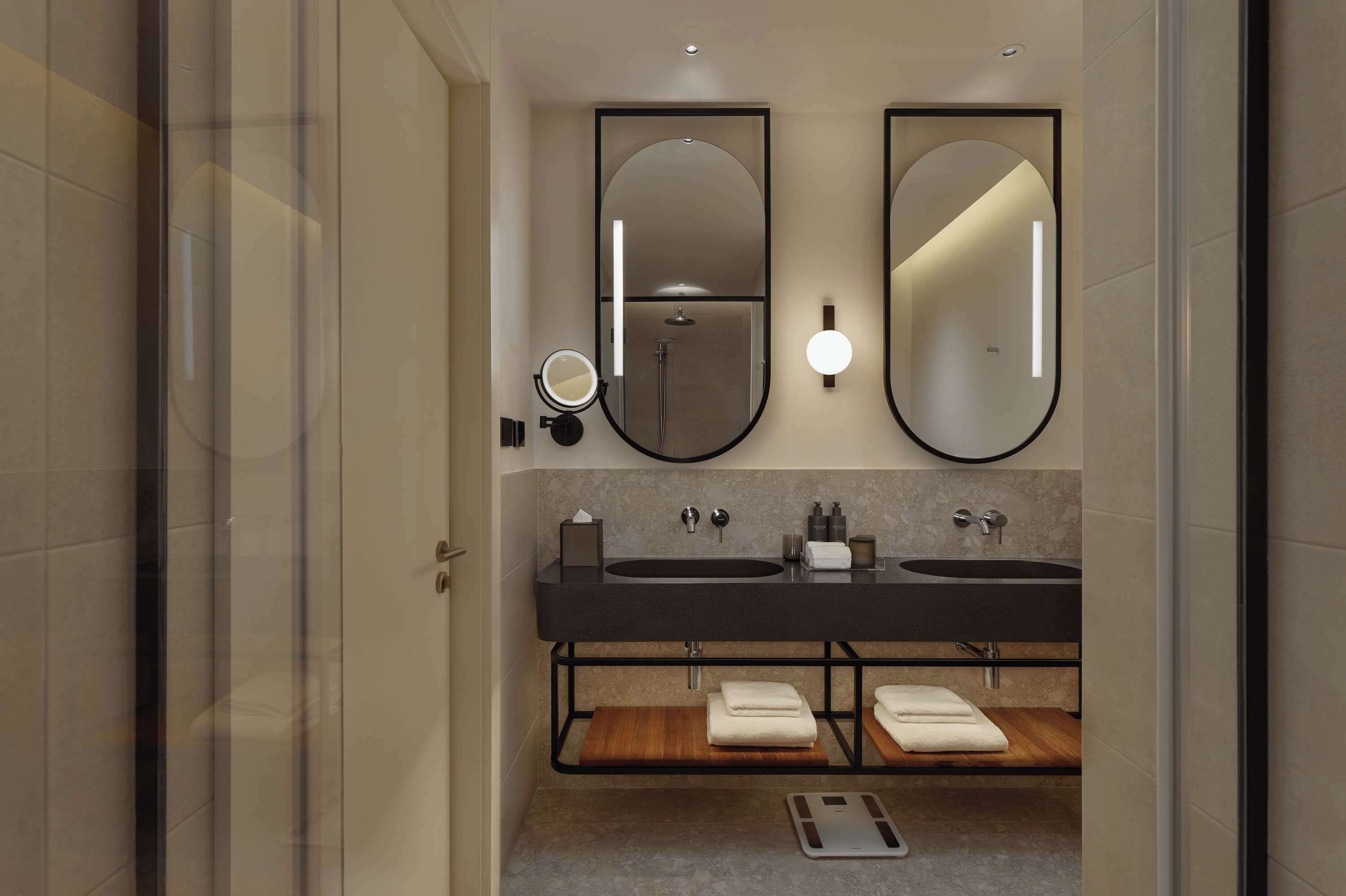 Un baño moderno con dos lavamanos, un espejo grande y una ducha.