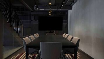 A conference room with a large table, six chairs, a TV screen, and a staircase.