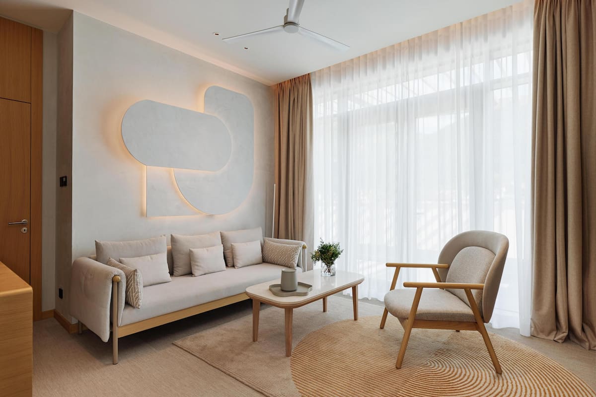A modern living room with a sofa, armchair, coffee table, and a unique wall art piece.