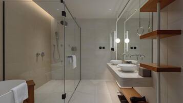 A modern bathroom with a glass-enclosed shower, a white bathtub, and a vanity with two sinks.