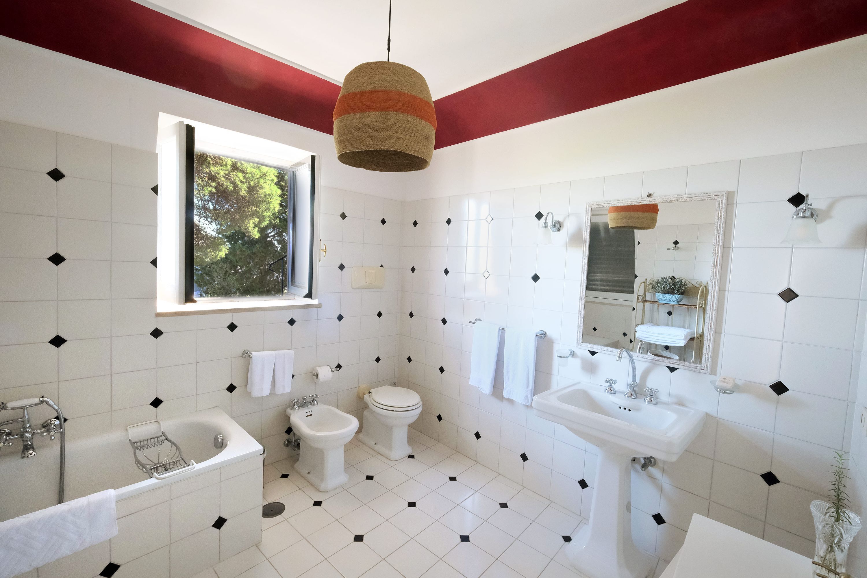 A bathroom with a bathtub, toilet, sink, and window.