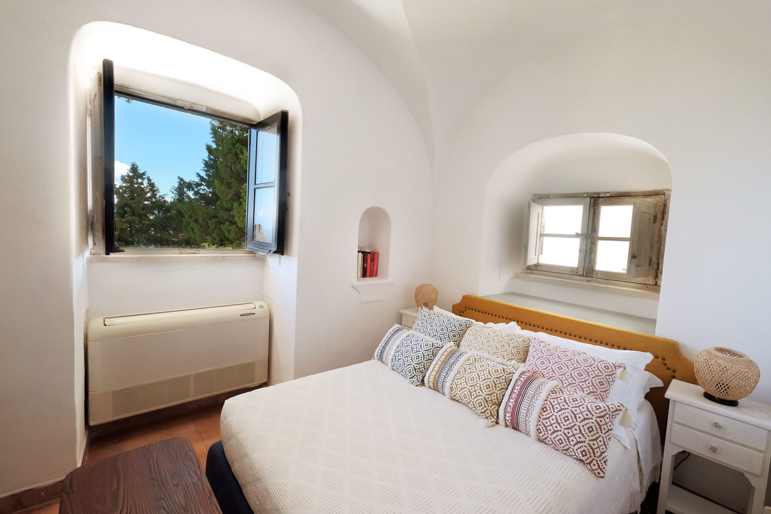 Un dormitorio con cama, mesita de noche, ventana y calefacción integrada.