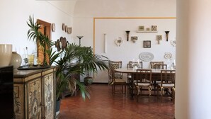 A dining area with a wooden table and chairs, surrounded by potted plants and decorative wall art. - Villa Amelia in Capri (Capri)
