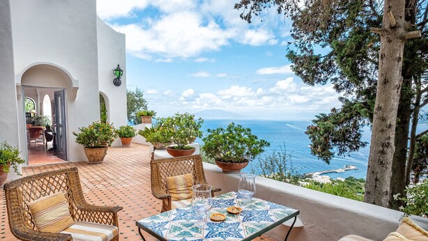 A terrace with wicker furniture, a tiled table, and potted plants. - Villa Amelia in Capri (Capri)