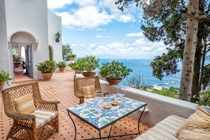 A terrace with wicker furniture, a tiled table, and potted plants. - Villa Amelia in Capri (Capri)