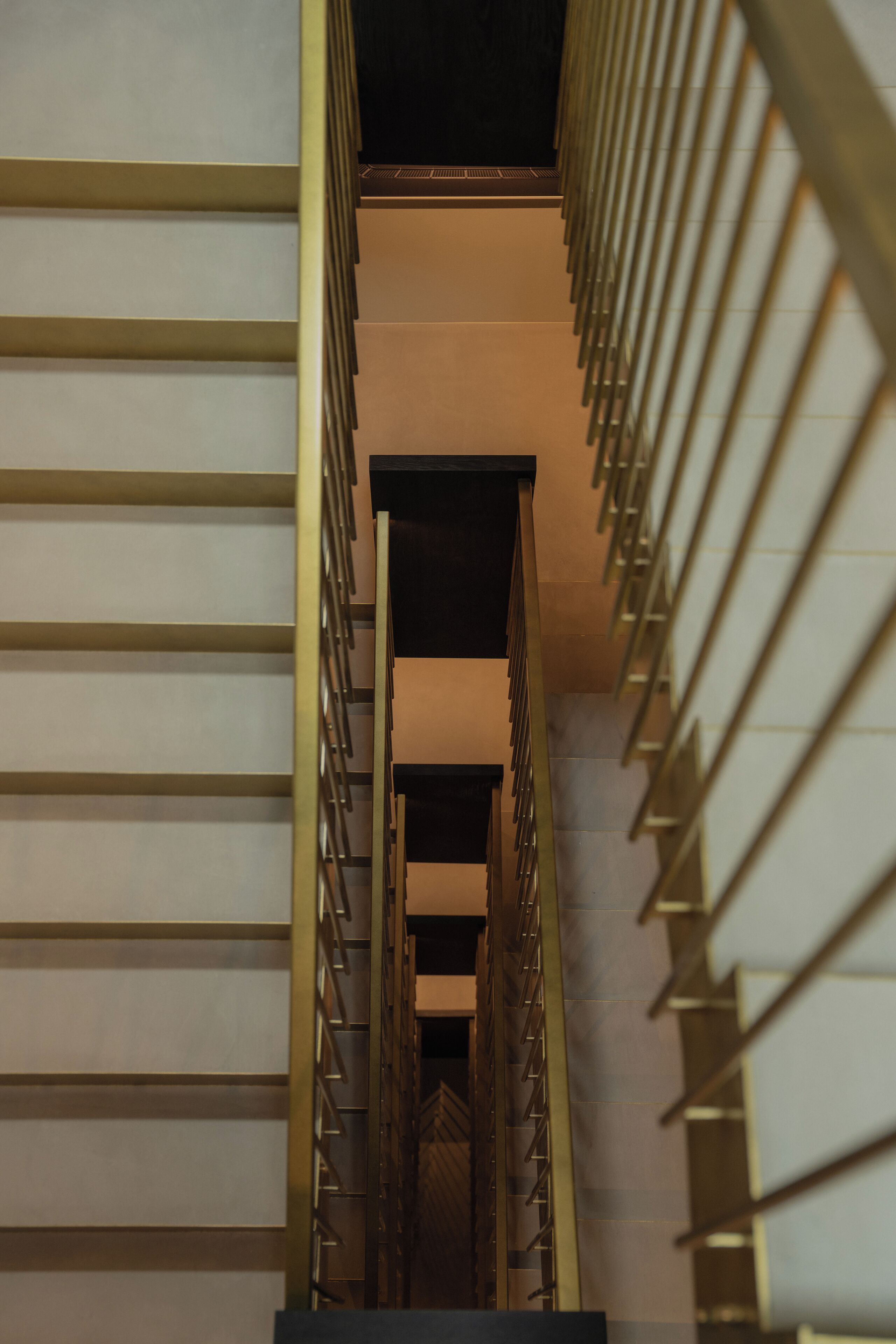 Una escalera moderna con barandilla metálica y pared en tonos neutros.