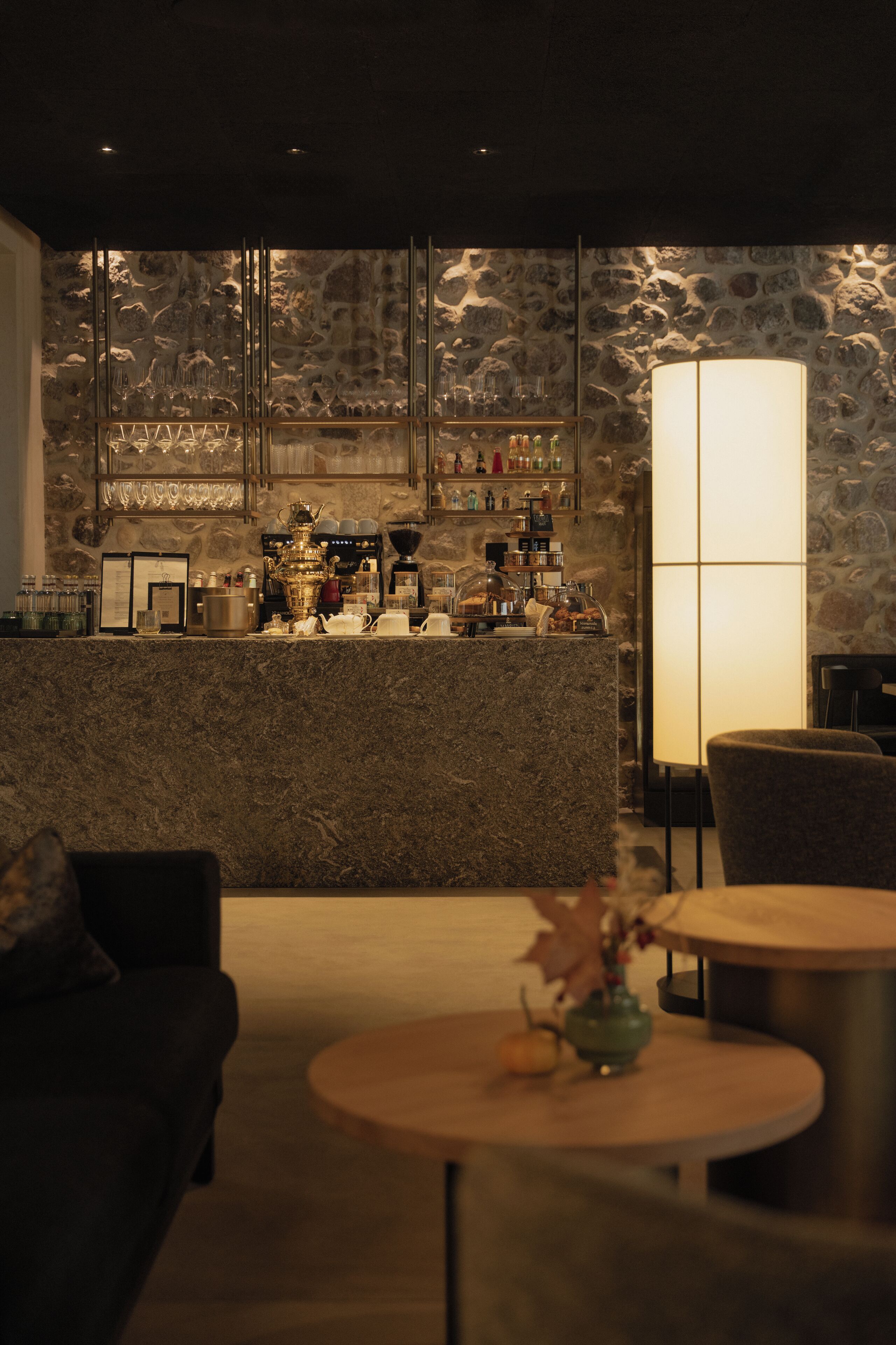 Een bar met een stenen achtergrond, een toonbank met verschillende spullen en een tafel met een vaas.