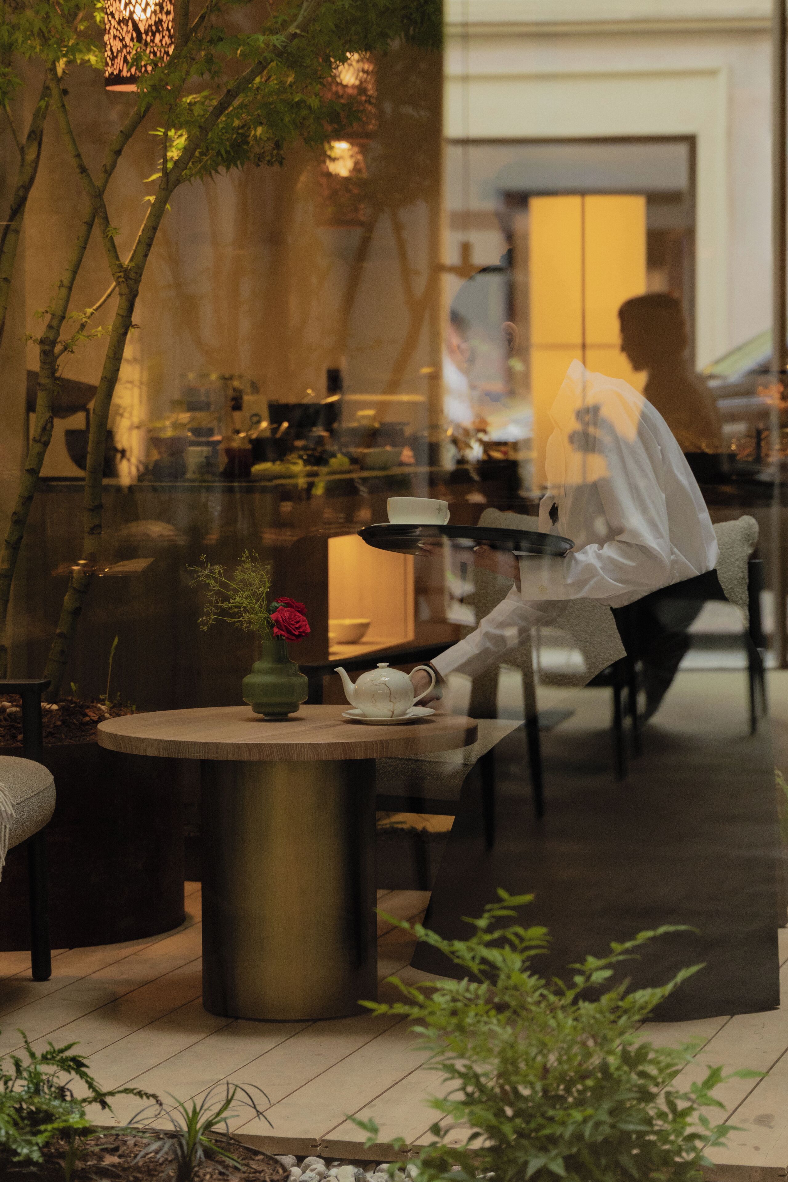 A modern outdoor seating area with a round table, a vase with a flower, and a teapot.