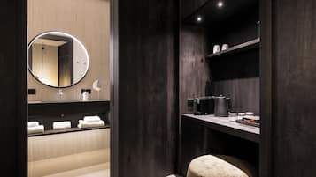 Une salle de bain moderne avec des finitions en bois foncé, un miroir rond, un meuble-lavabo et un tabouret rond.