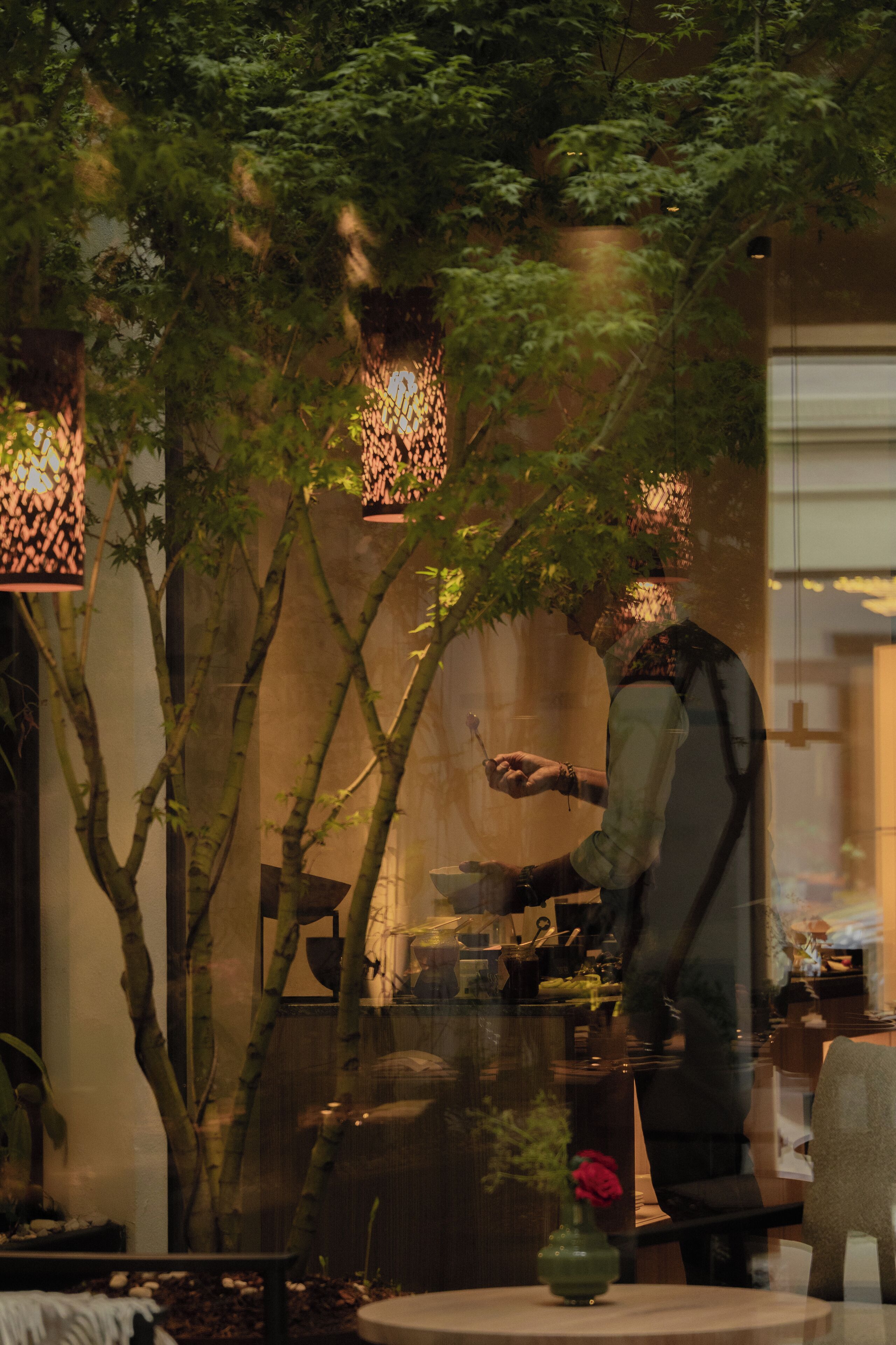 A restaurant with bamboo plants and hanging lights.