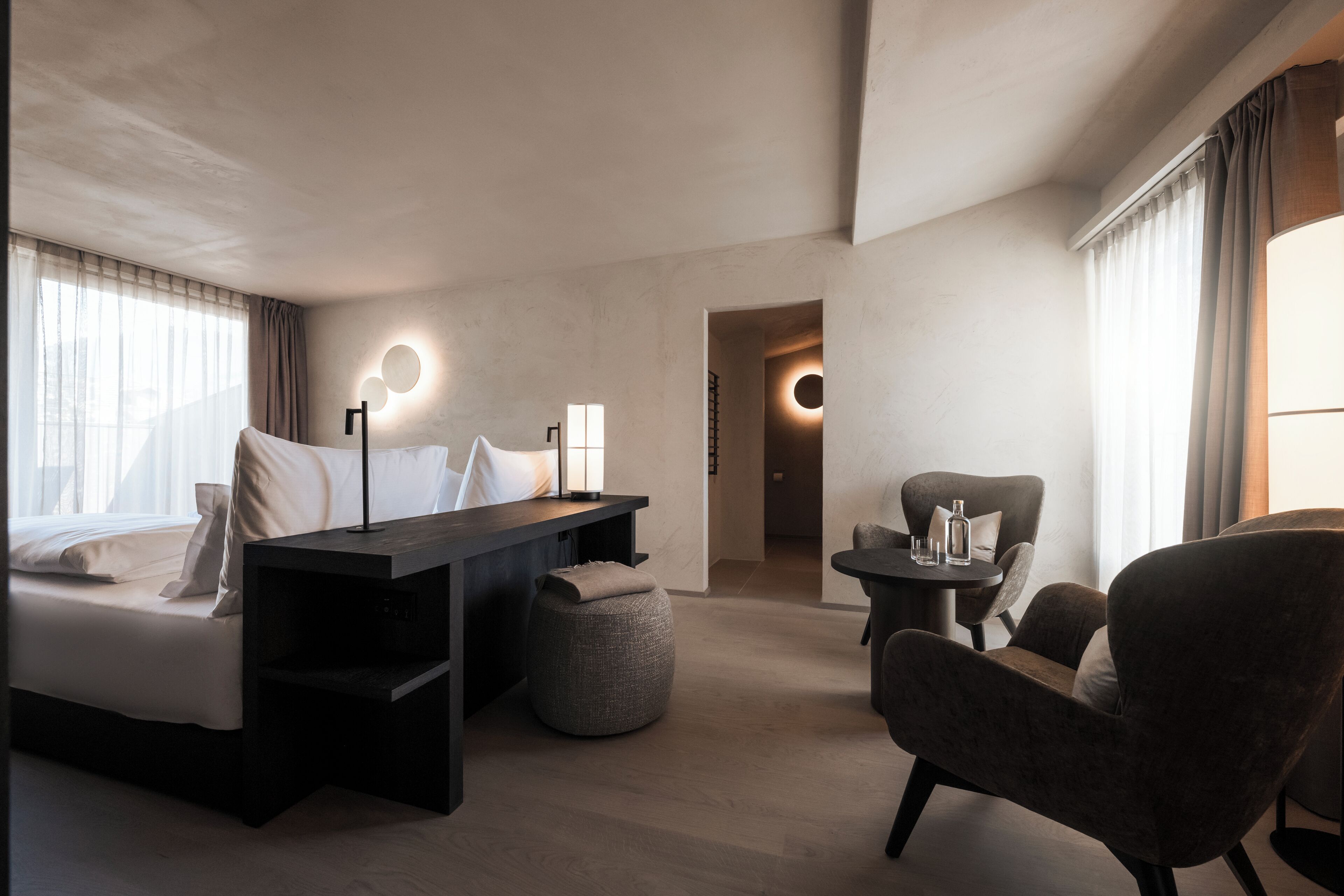 Une chambre d’hôtel moderne équipée d’un lit, d’un bureau, d’une chaise et d’une petite table.
