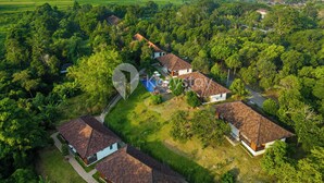 An aerial view of a residential area with houses, a swimming pool, and surrounding greenery. - Kana Village Villa by Kozystay (Tabanan)