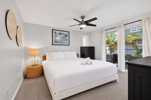 A hotel room with a bed, a ceiling fan, a window with curtains, a wall-mounted artwork, and a side table with a lamp. - One Block To Mission Beach and Belmont Park! (San Diego)