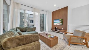 Een moderne woonkamer met een bank, salontafel, televisie en een fauteuil.