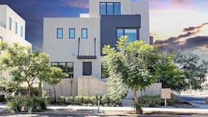 A modern building with a flat roof, large windows, and a staircase leading to the entrance.