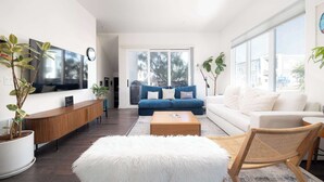 A modern living room with a sofa, coffee table, and a white furry ottoman.