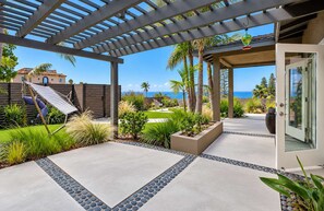 A patio area with a pergola, a hammock, and a view of the ocean.