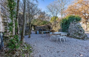 Secluded seating area surrounded by trees and vegetation, featuring a wooden table and chairs.