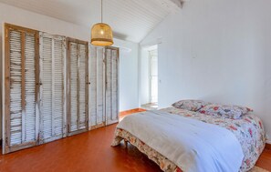 Cozy retreat with a large bed, floral-patterned duvet, and woven pendant light.