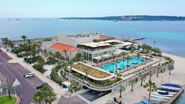 Ein Resort mit Swimmingpool, Palmen und Blick auf das Meer.