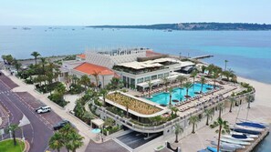 A resort with a swimming pool, palm trees, and a view of the sea.