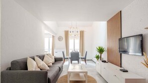 Ein modernes Wohnzimmer mit grauem Sofa, einem Couchtisch und einem an der Wand befestigten Fernseher.