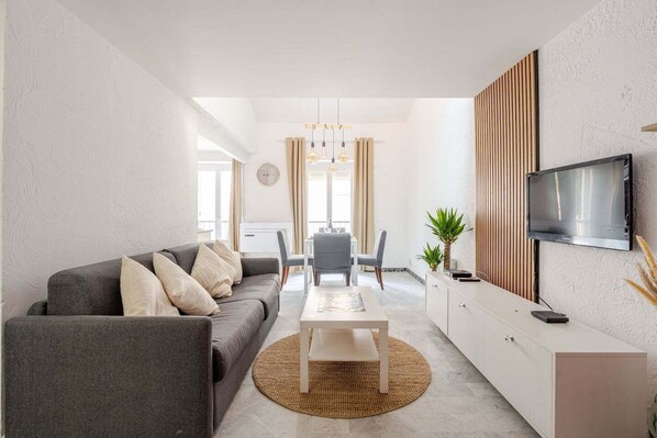 A modern living room with a grey sofa, a coffee table, and a TV mounted on the wall.