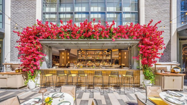 Ein Außenbereich mit Bar, Sitzgelegenheiten und einem Blumenschmuckbogen.