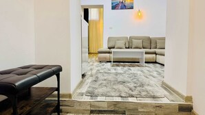 Una sala de estar con un sofá, una mesa de centro, un banco y una alfombra.