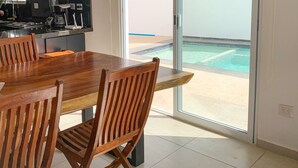 A modern kitchen with a dining area and a view of a pool. - Casa con alberca propia-Almarena (Mazatlán)