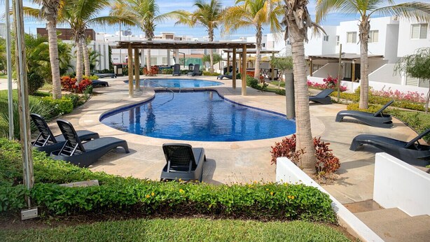 A swimming pool with lounge chairs and palm trees. - Casa con alberca propia-Almarena (Mazatlán)