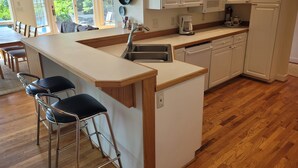 Een moderne keuken met een centraal eiland, barstoelen, een vaatwasser en een magnetron.
