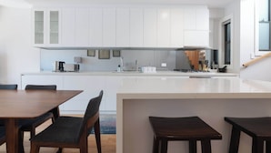 A modern kitchen with white cabinetry, a central island, and a dining area with wooden furniture.