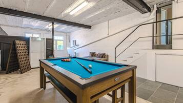 Une table de billard avec des billes, un banc en bois et un escalier.