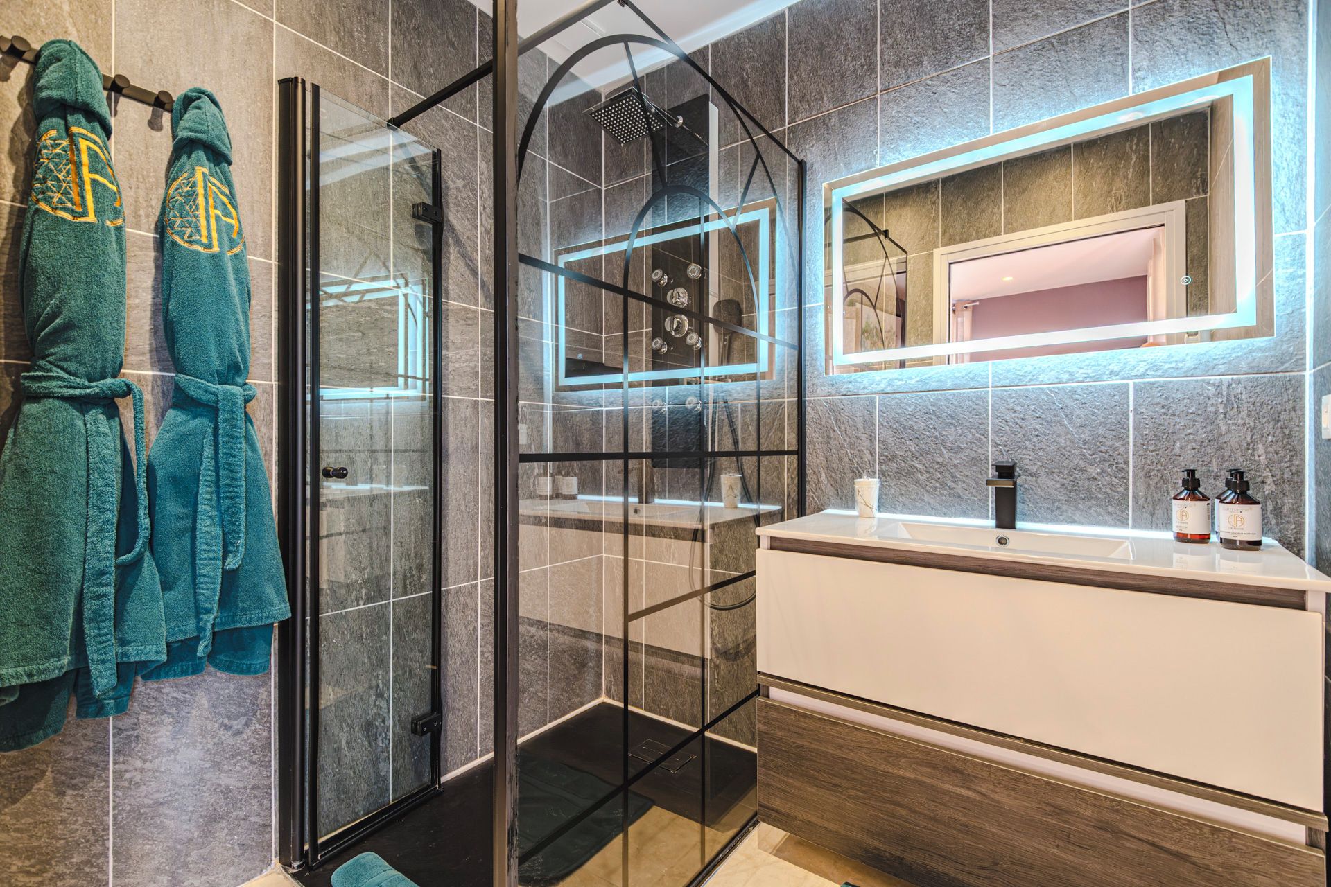 Une salle de bain moderne avec une douche à parois de verre, un meuble-lavabo avec un miroir et deux serviettes suspendues sur un porte-serviettes.