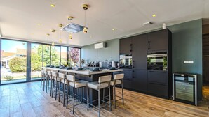 Une cuisine moderne dotée d’un îlot central, de tabourets de bar et offrant une vue sur l’extérieur.
