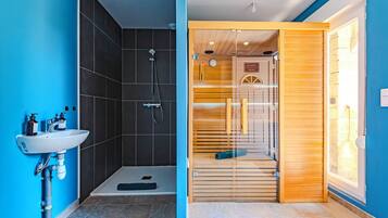 Een moderne badkamer met een douche, een wastafel en een houten deur naar de douchecabine.