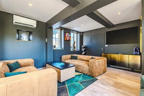 Un salon moderne avec un canapé d’angle, une table basse et un téléviseur à écran plat.