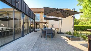 A modern outdoor dining area with a table and chairs, a large umbrella, and a gravel patio.