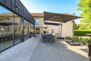 A modern outdoor dining area with a table and chairs, a large umbrella, and a gravel patio.
